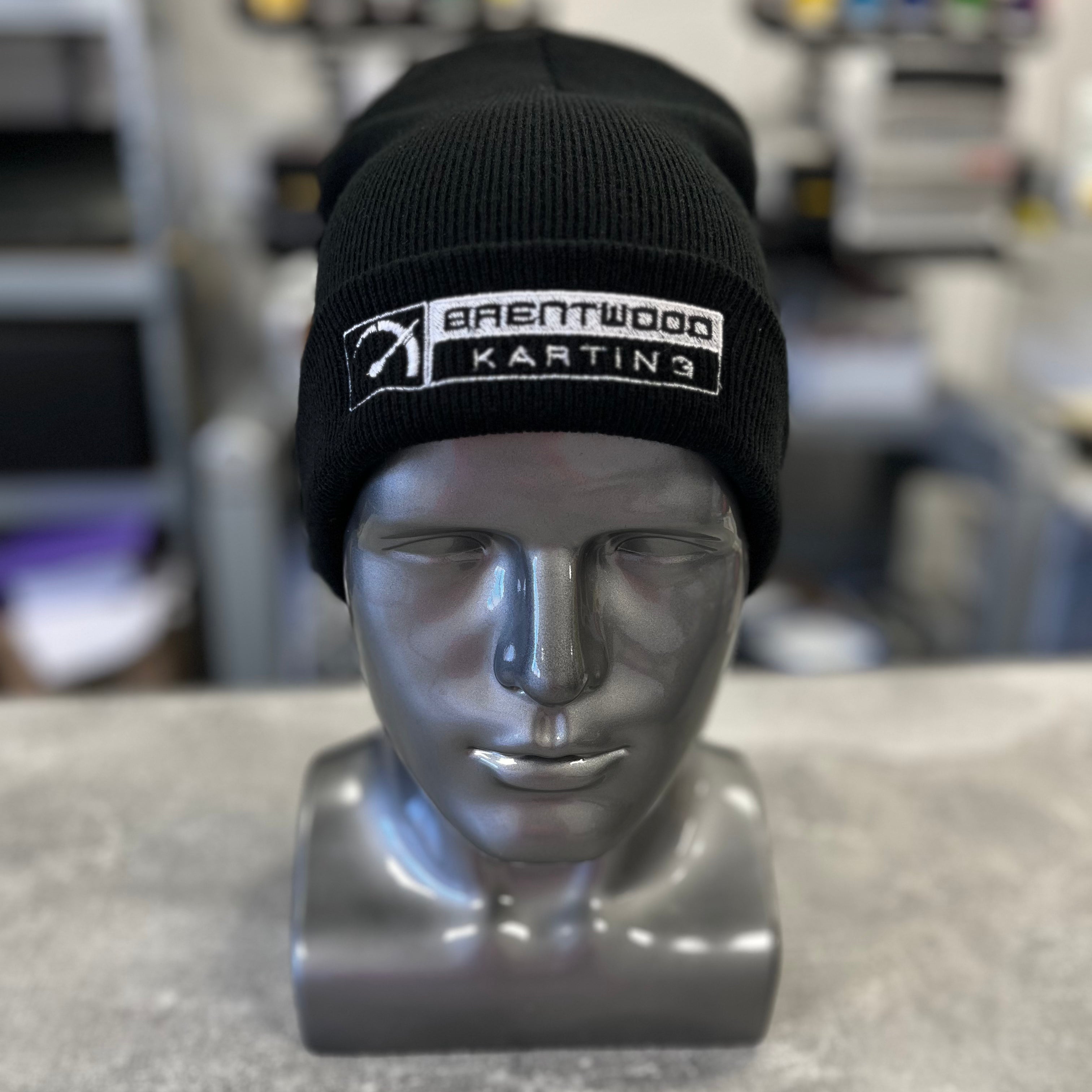 Black knitted beanie hat embroidered with the Brentwood Karting logo, showcased on a silver mannequin head, part of the official branded merchandise collection.