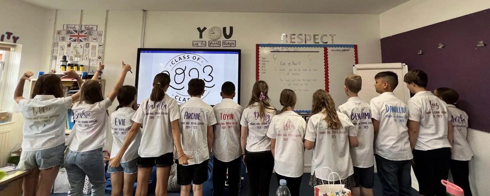 Group of children wearing personalised Thorpe Hall School leavers shirts, standing together in a classroom.