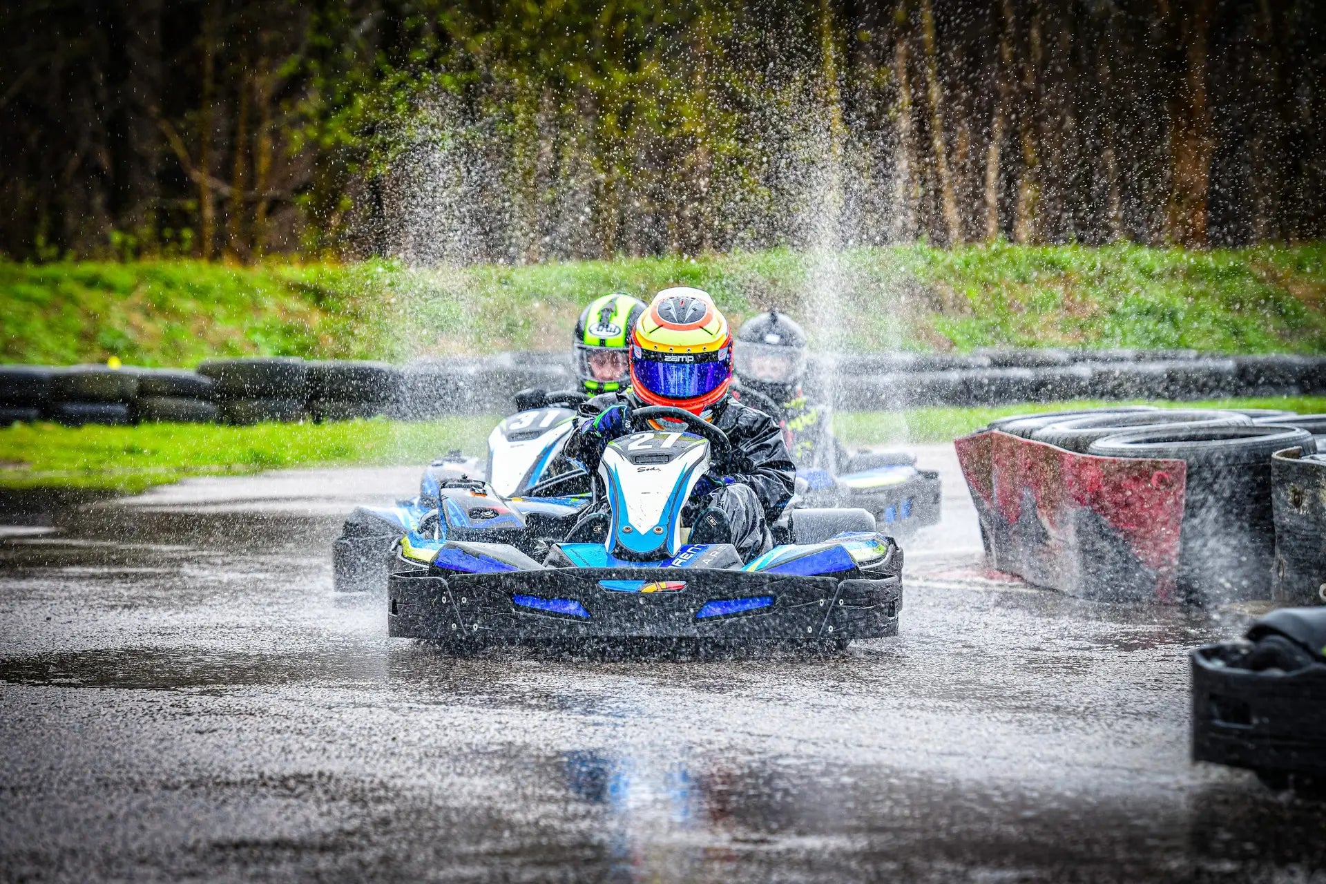 High-speed racing action at Brentwood Karting as drivers navigate a wet track, with intense water spray adding to the challenge of competing in rainy conditions.